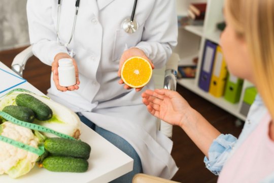 Close-up-doctor-with-pills-container-and-half-orange-1024x68