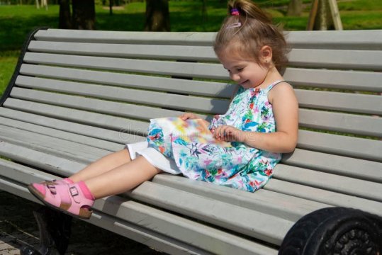 Little-girl-sits-bench-park-reads-book-little-girl-sits-benc